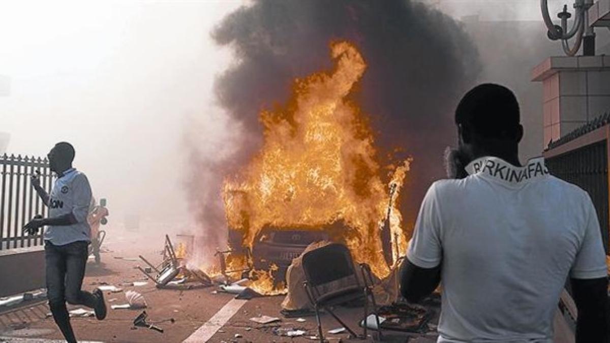 Un manifestante observa el fuego provocado en un vehículo estacionado junto al Parlamento el jueves.