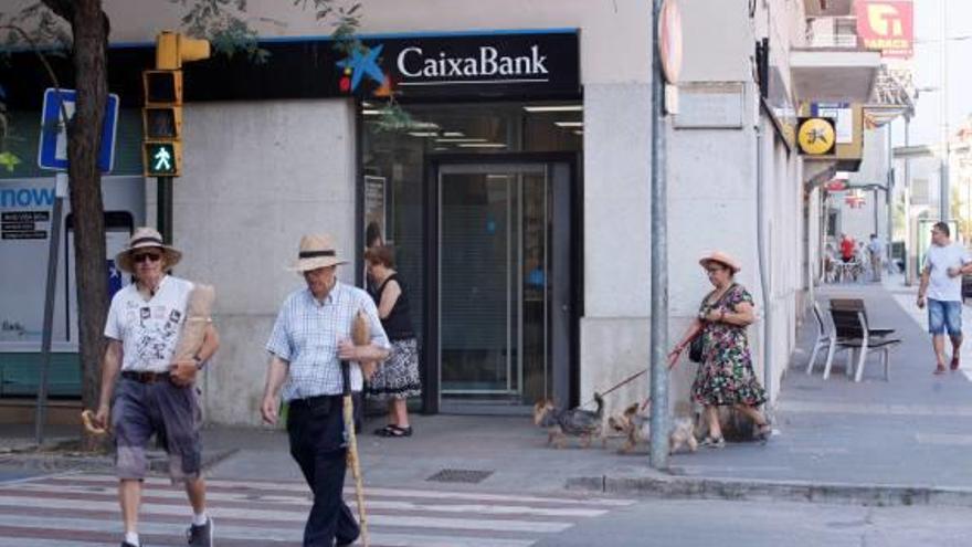 Veïns, caminant per davant de la Caixa, que tancarà en breus.