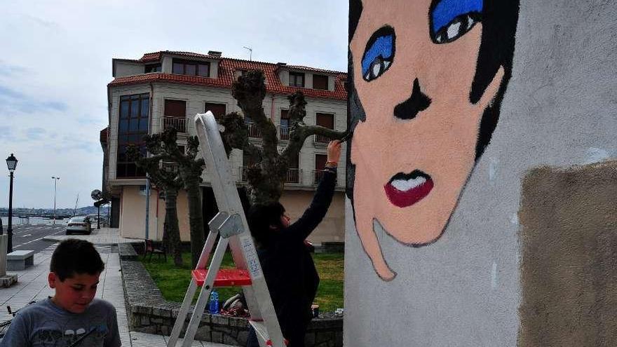 Alumnos del Faro das Lúas pintando el mural de Rosalía en el paseo marítimo de O Cabo.  // Iñaki Abella