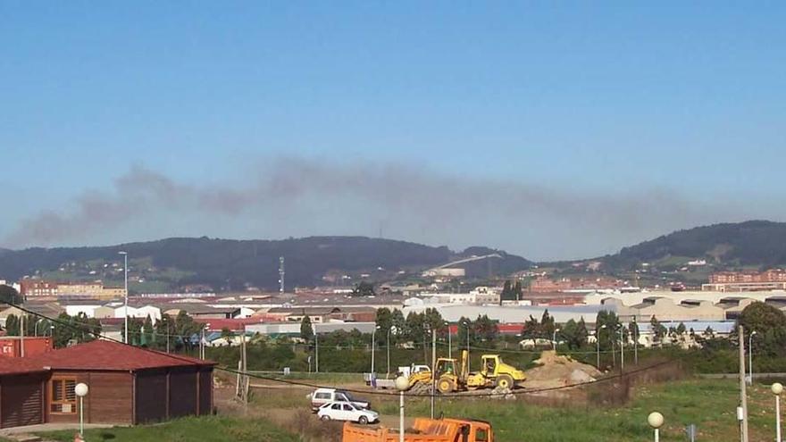 Al fondo, un penacho de humo que sale de una de las chimeneas del sínter de Arcelor Mittal en Gijón, en una imagen tomada desde las inmediaciones del ambulatorio de Pumarín.