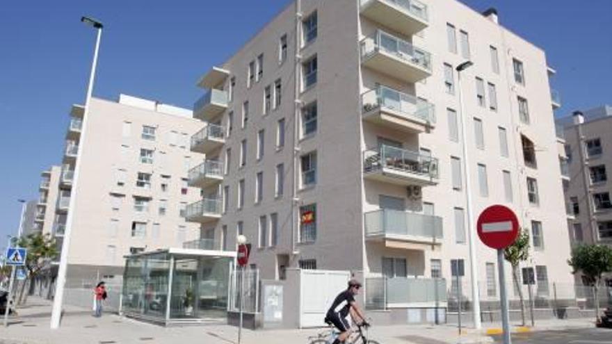 Un ciclista pasa junto a una promoción de pisos de protección oficial en Elche