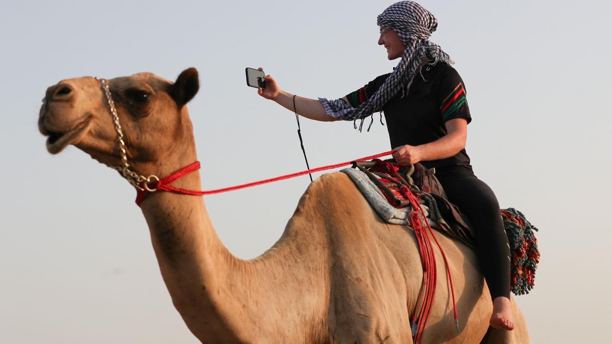 Sarah Collins monta en camello por el desierto emiratí.