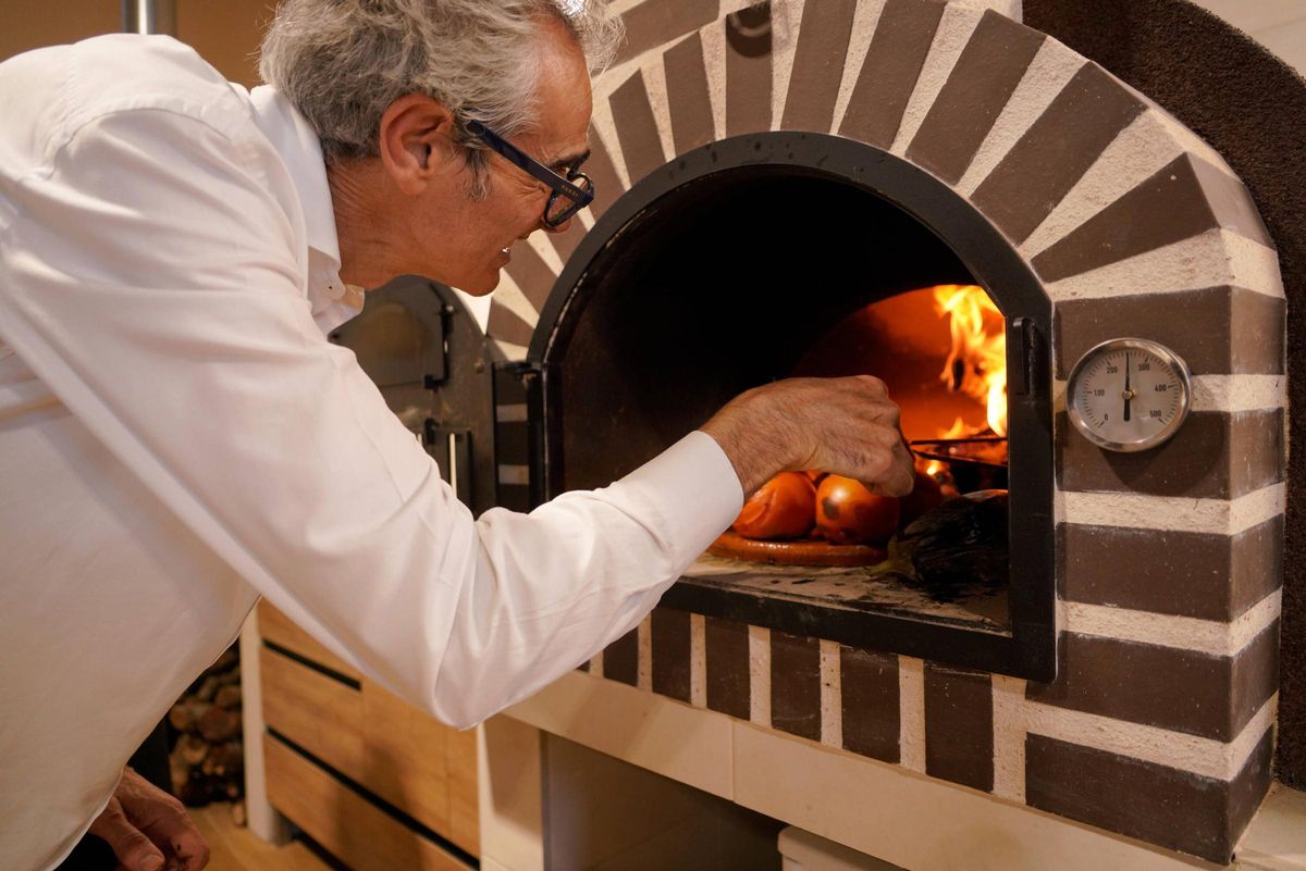 Antonio González, supervisa unas verduras asadas en un horno de leña de la Escuela