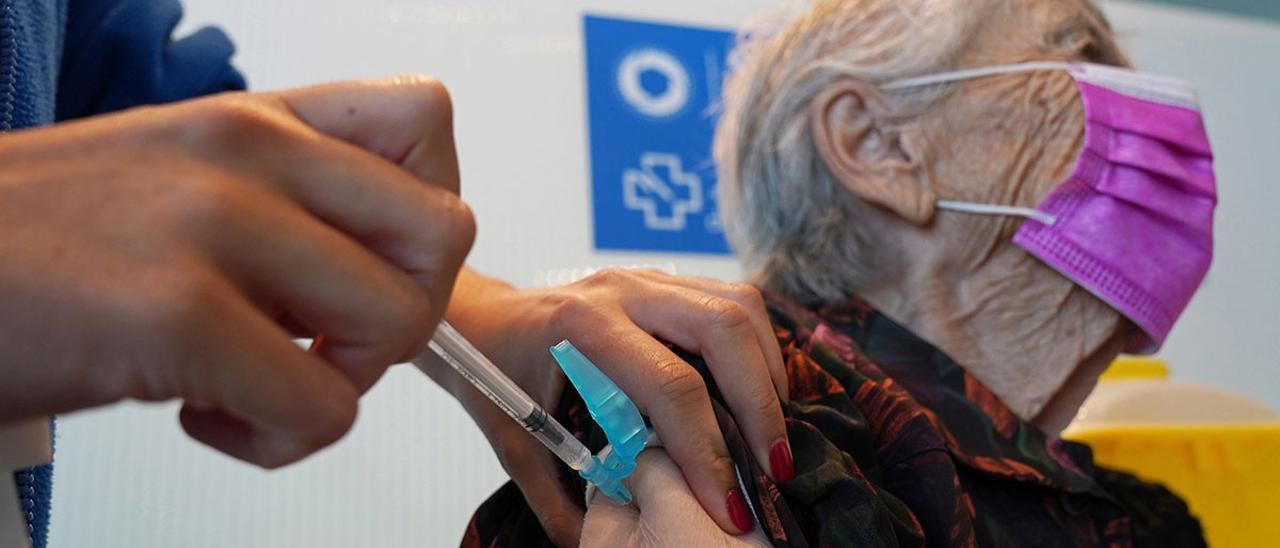 Personal sanitario vacunando a una mujer mayor.