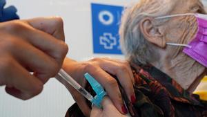 Personal sanitario vacunando a una mujer mayor.