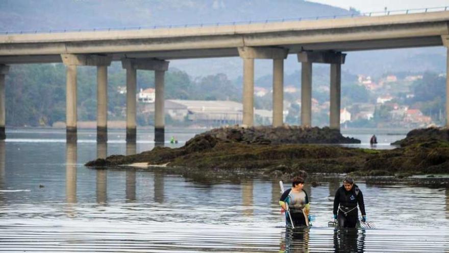 Dos mariscadoras ante el puente de la autovía en Taragoña bajo el cual se encontró el teléfono.