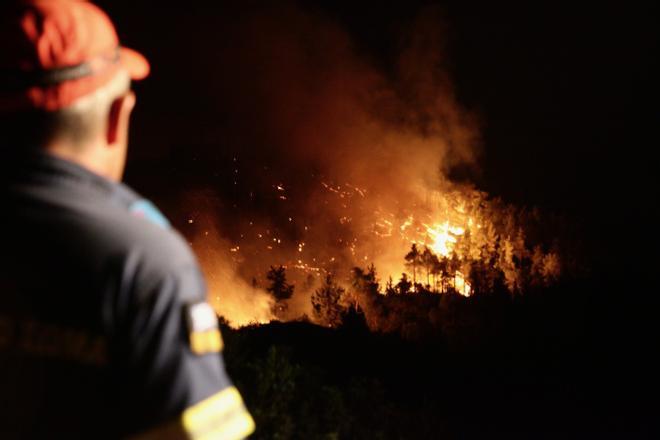 23 July 2023, Greece, Rhodes Island: A firefighter tries to put out a wildfire in Asklipio village, on Rhodes Island. Large fires have broken out on the Greek islands of Rhodes and Corfu and in numerous other regions of Greece, which has been suffering a