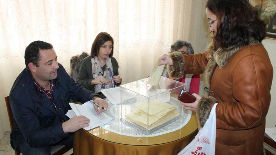 Una madre deposita su voto en la urna instalada en el colegio de Noreña.