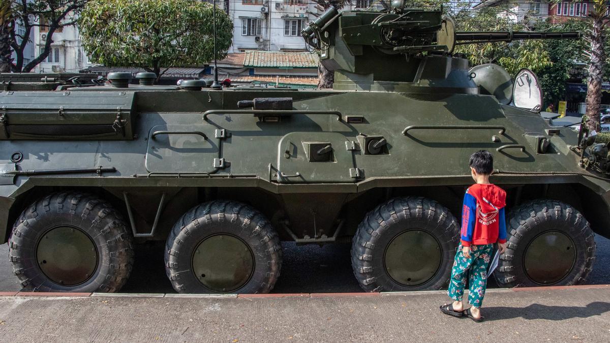 Un niño juega junto a un vehículo militar en Rangún.