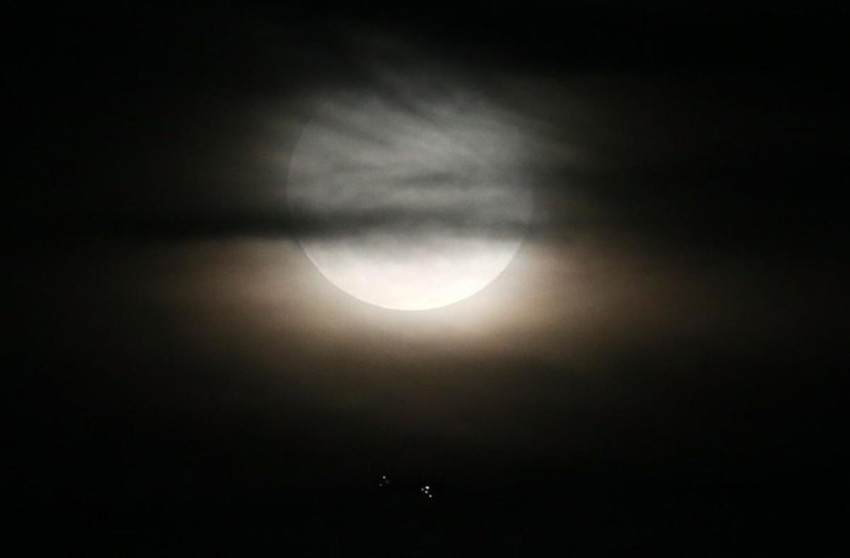 Un avión cruza los cielos mientras la superluna se eleva en el firmamento de Río de Janeiro (Brasil), el 10 de agosto de 2014.