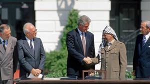 El expresidente de EEUU Bill Clinton saluda al presidente palestino Yasir Arafat durante la firma de los Acuerdos de Oslo en 1993, en presencia del primer ministro de Israel Isaac Rabin (centro-izquierda).