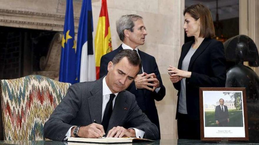 El Rey, firmando; detrás, Yves Saint-Geous y la reina Letizia. reuters