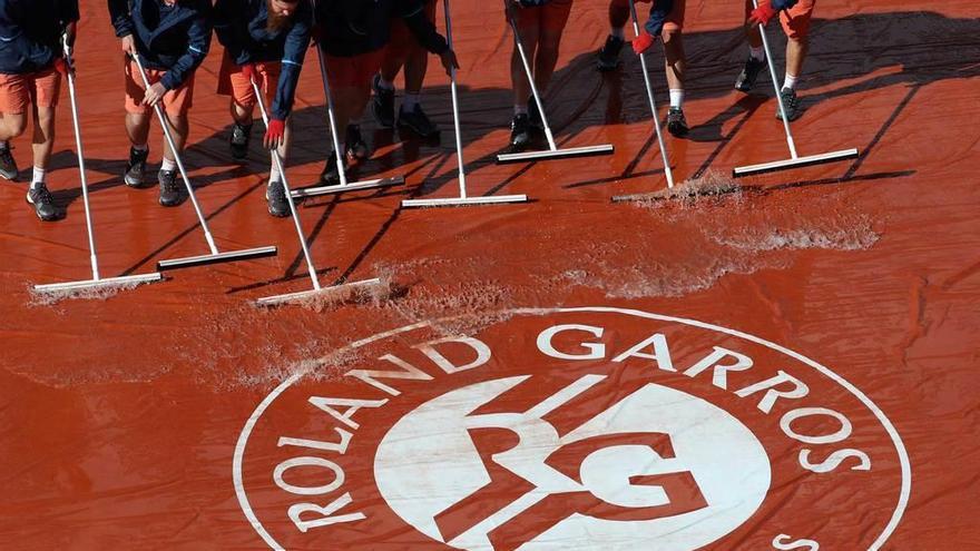 Los operarios achican agua en la pista central, ayer en Roland Garros.