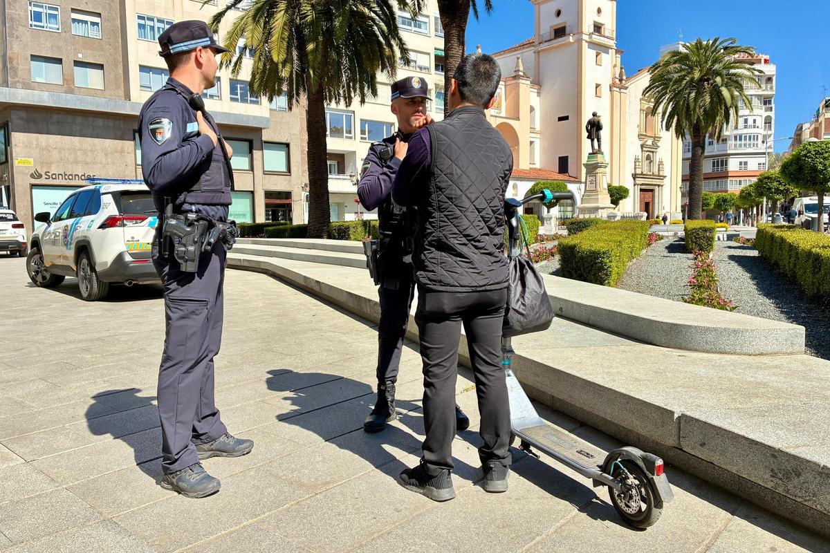Agentes de la Policía Local junto a un usuario de patinete eléctrico en la plaza Minayo de Badajoz.