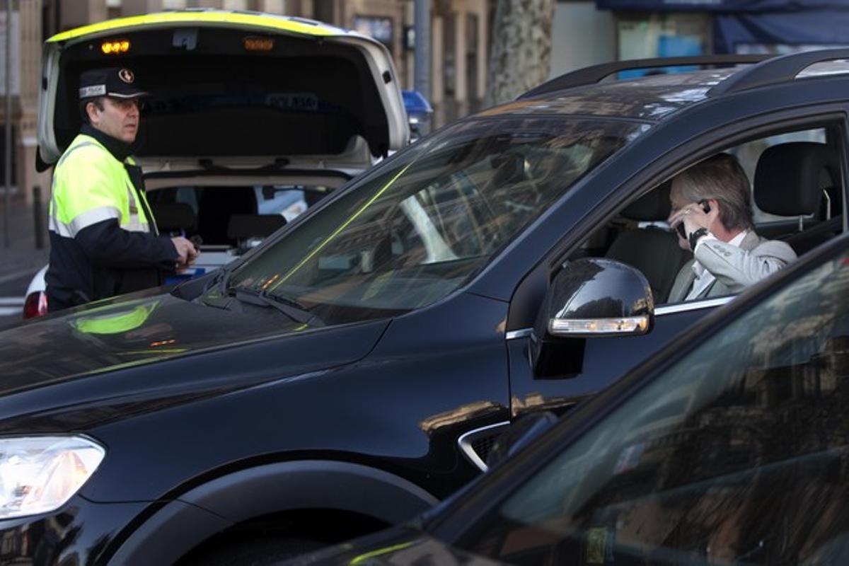 Un Guardia Urbano multa a un conductor en Barcelona.