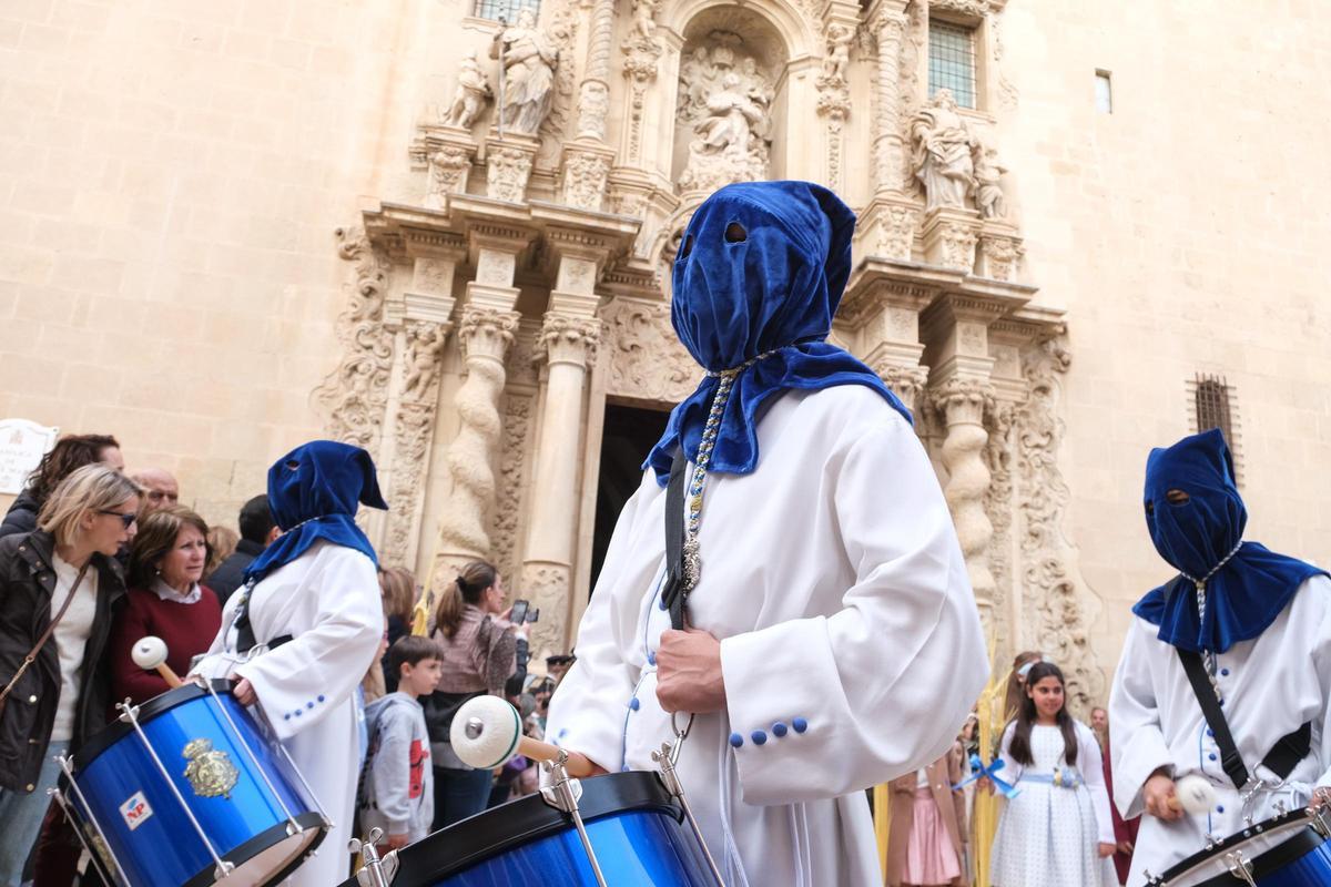 Los cofrades de San Pedro Apóstol en Alicante procesionan ataviados de vesta blanca y capirote azul.