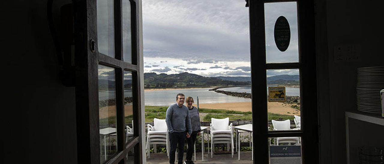 Juan Ramón Coto y Lilián Vázquez, en la terraza desmantelada de su restaurante de Rodiles, con la ría de Villaviciosa al fondo.