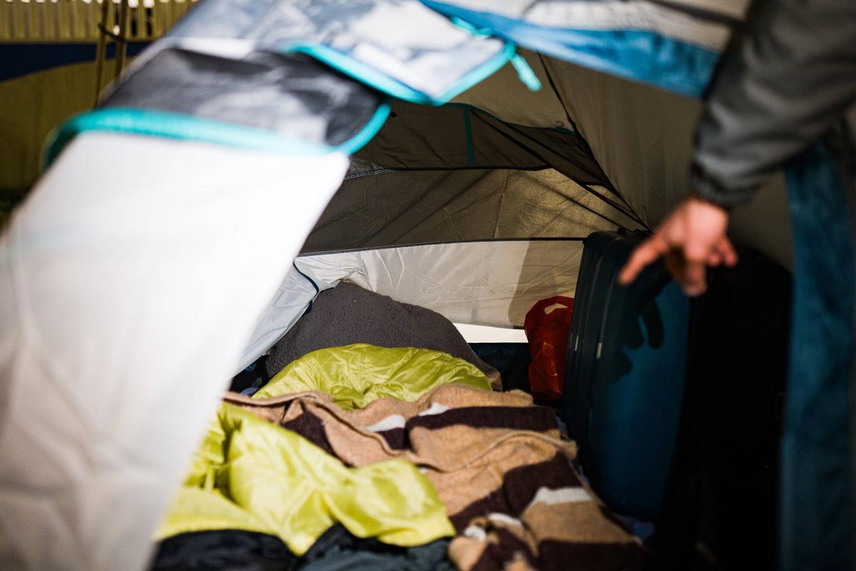 Un hombre señala la tienda de campaña donde duerme, en la Zona Franca de Barcelona.