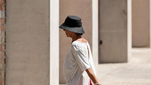 Una dona de protegeix del sol i la calor amb un barret.