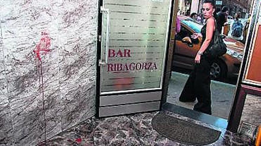 El bar en el que pidió auxilio el herido, con la mancha de sangre que dejó al apoyarse en la pared.