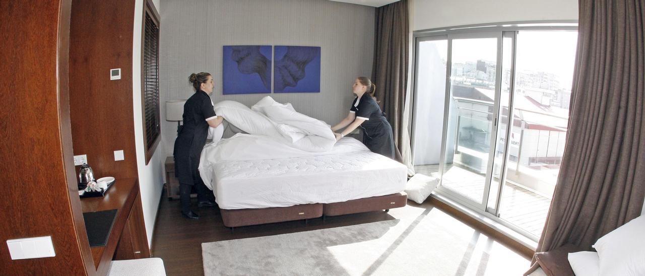 Dos trabajadoras, haciendo la cama de una habitación.