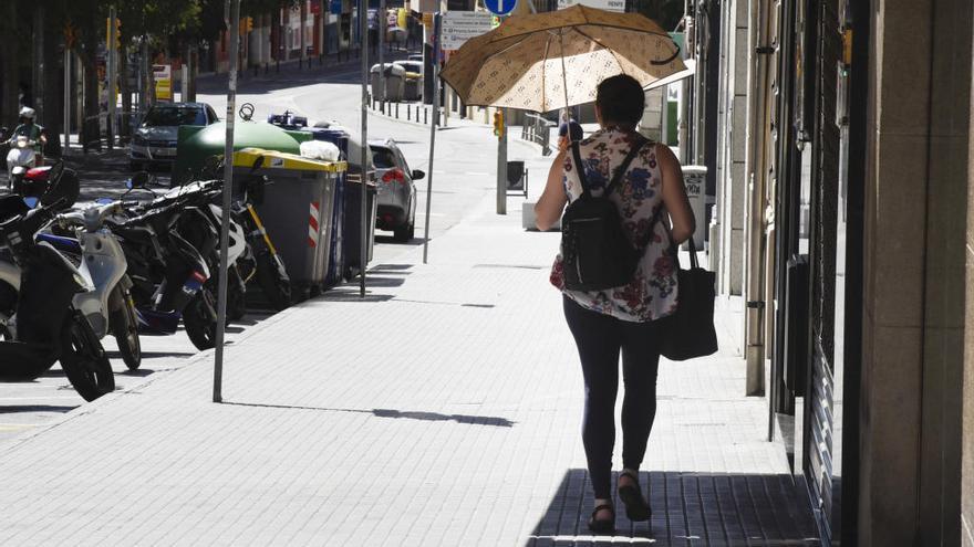 Dona protegint-se del sol amb un paraigua al centre de Manresa, divendres, 9 d&#039;agost.