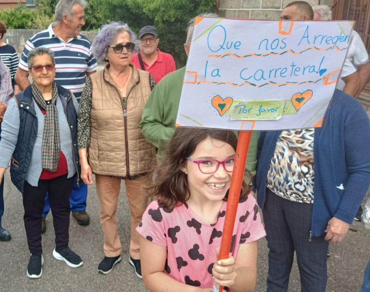 Una niña reclama con un cartel el arreglo de camino de O Couto en Reboreda (Redondela). Junio 2025. A.P.