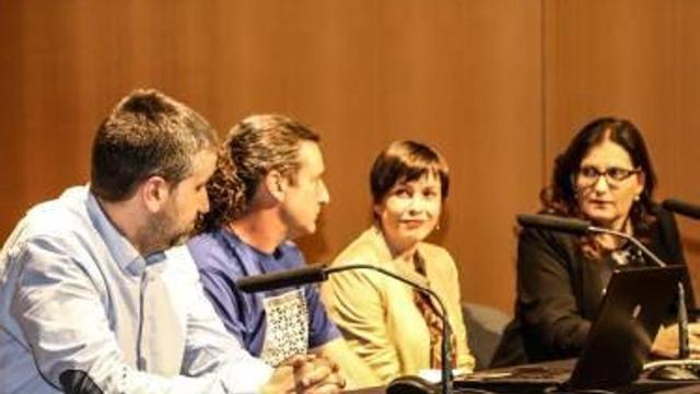 A la izquierda, imagen de la mesa formada por el investigador y los ediles. A la derecha, público.