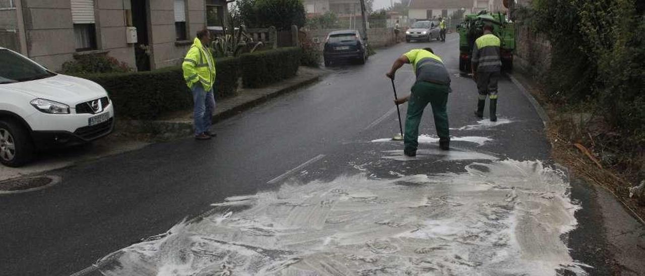 Los trabajadores de la empresa del camión limpian en la rúa Nova, en Beluso. // Santos A.