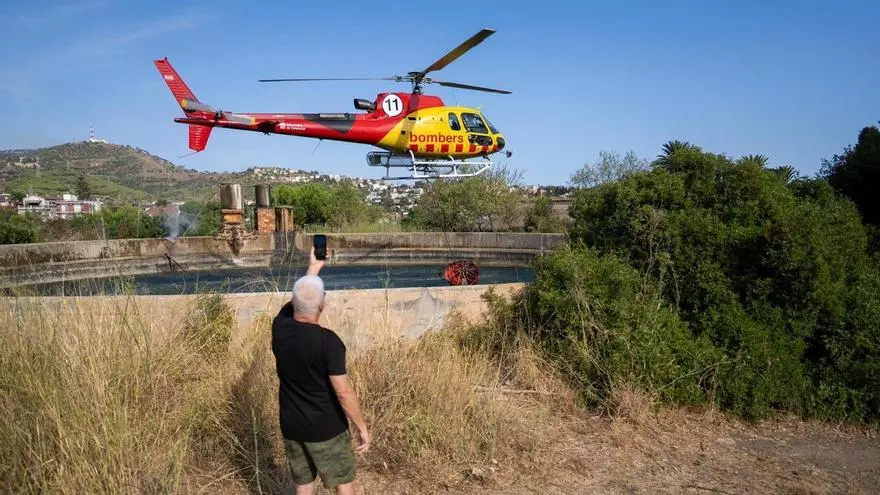 Un helicóptero carga agua para combatir el incendio de Collserola