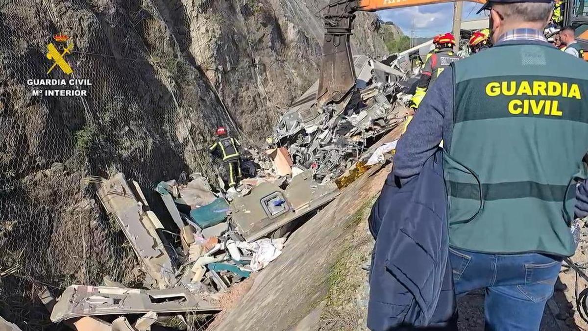 Un agente de la Guardia Civil observa el desescombro en torno a uno de los vagones del Alvia siniestrado en el término cordobés de Adamuz.