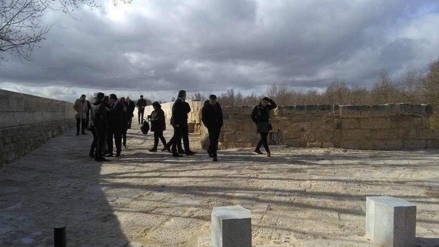 En primer plano, bolardos instalados en el acceso al puente de piedra para evitar el paso de vehículos.