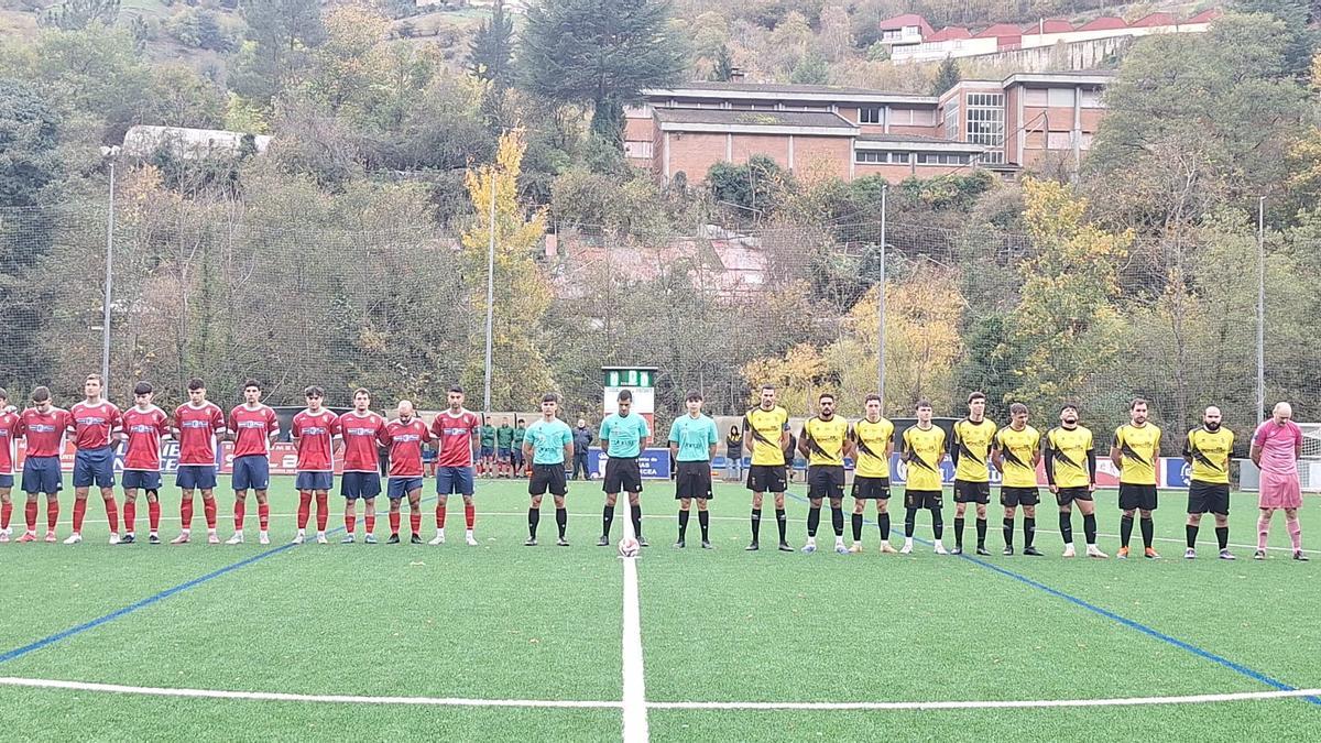 Los jugadores del Narcea, a la izquierda, y los del Vegadeo, a la derecha, antes del inicio del partido en El Reguerón durante el minuto del silencio.