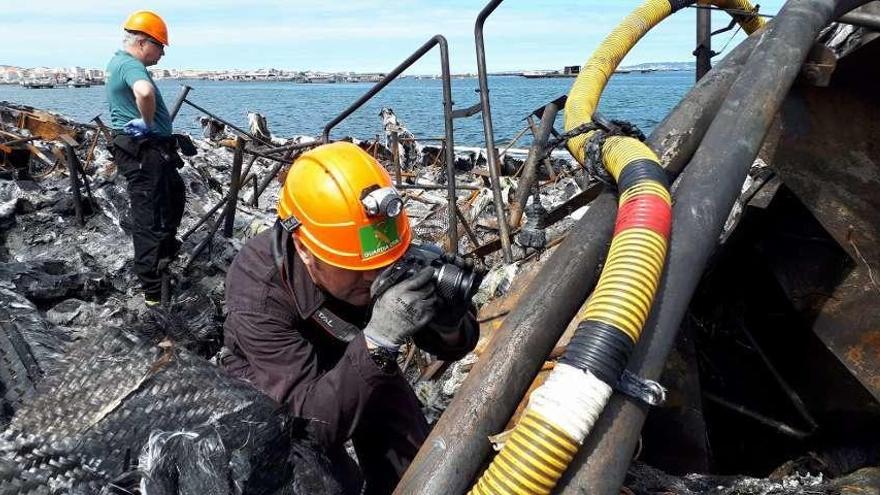 El Equipo de Investigación de Incendios de la Guardia Civil, con base en A Coruña, examinando los restos del catamarán en O Grove, ayer. // Guardia Civil