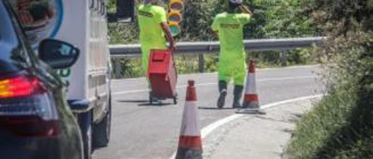 Dos operarios transitan por la carretera con la cuneta ya rebajada. A la derecha, uno de los tramos en los que todavía se aprecia la profundidad de la zanja.