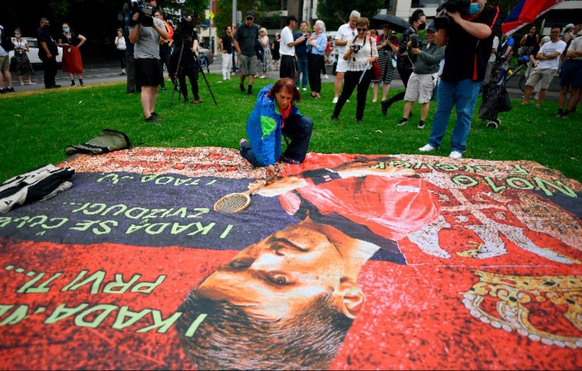 Simpatizantes de Novak Djokovic despliegan una pancarta de apoyo al tenista serbio frente al hotel en el que se haya confinado, este viernes, en Melbourne.