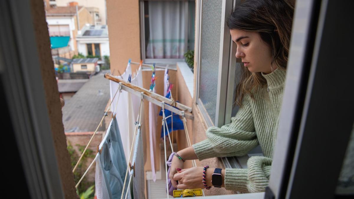 Una joven tiende la ropa en su vivienda.