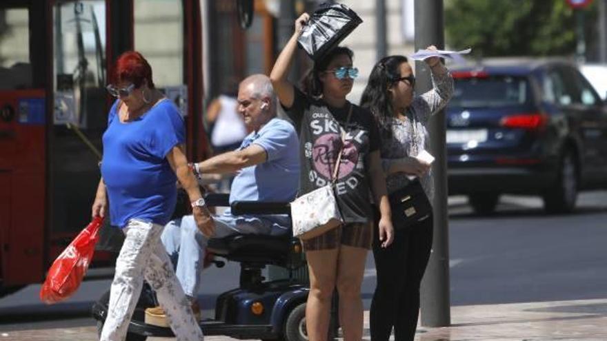 Dos jóvenes se cubren del sol en el centro de València.