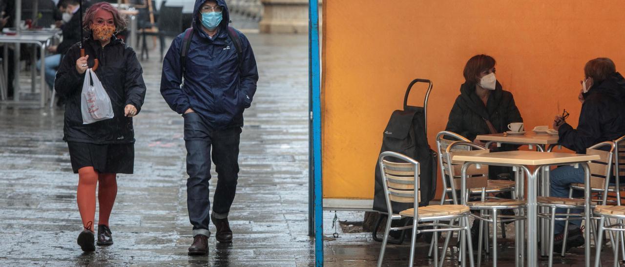 Paseantes y clientes de una terraza, con mascarilla.