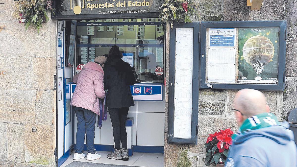 Dos personas comprando lotería de Navidad ayer en la administración número 3 de Santiago