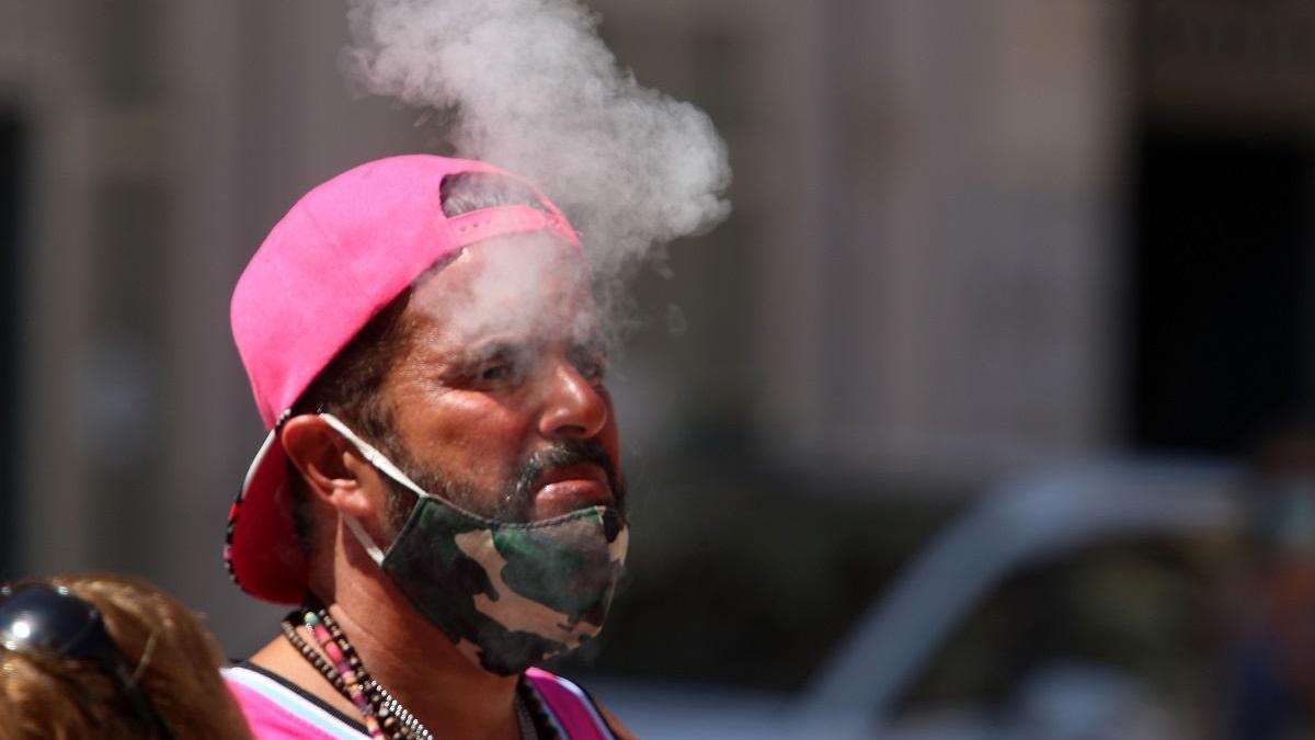 Un ciudadano fumando con la mascarilla bajada.