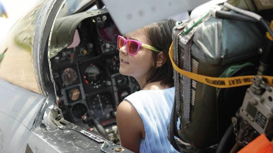 Una niña subida en la cabina del caza.