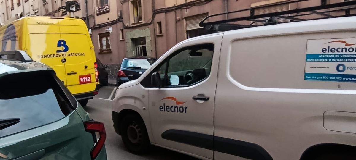 Un vehículos de bomberos y una furgoneta de mantenimiento, frente al portal afectado,
