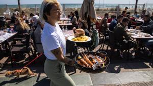 Una camarera sirve platos a sus clientes en un restaurante de Gavà.