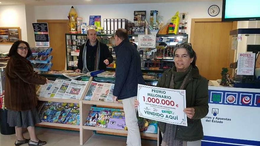 Leticia Allende enseña el cartel del premio, mientras Alfredo Villarías, detrás del mostrador, atiende a dos clientes, ayer en Ribadesella.