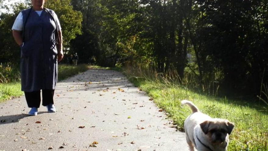 Isolina Noriega pasea con su perro por el paseo del ríu Chicu.