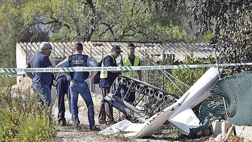 Guardias civiles y expertos del ministerio de Fomento inspeccionan los restos del ultraligero.