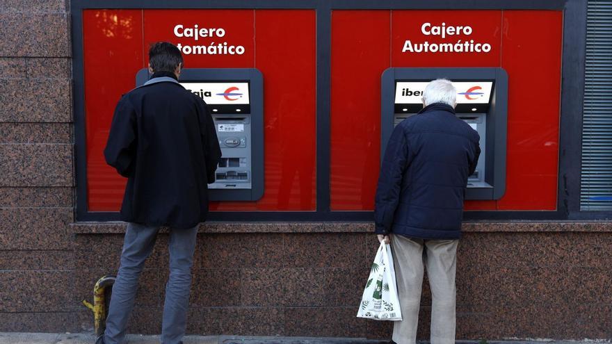 Dos personas sacan dinero en un cajero automático de Ibercaja en Zaragoza, en una imagen de archivo. | MIGUEL ÁNGEL GRACIA