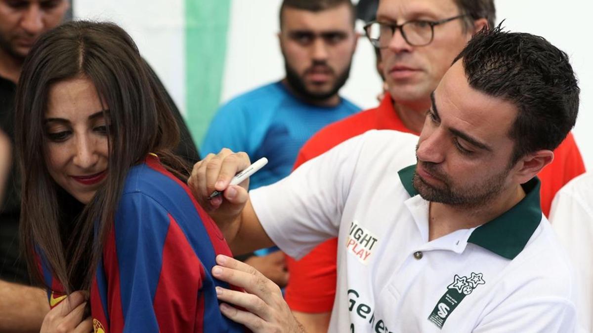 Xavi firma un autógrafo en la camiseta de una joven, este jueves en el campo de refugiados de Baqa.