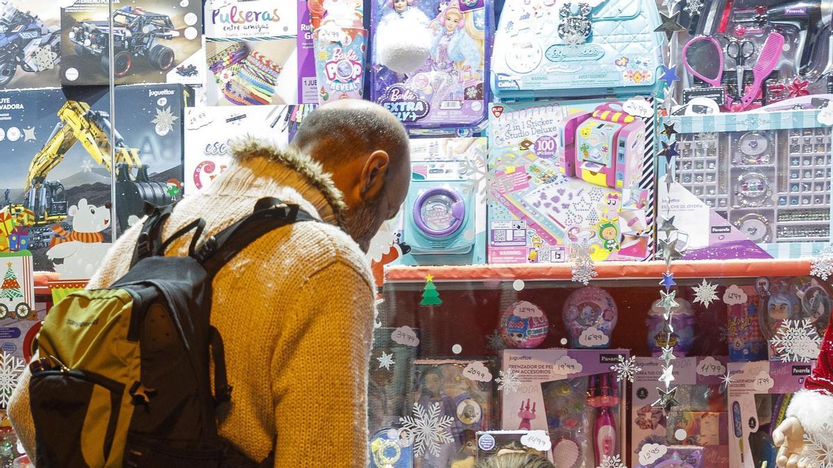 Un hombre mira un escaparate con juguetes infantiles.